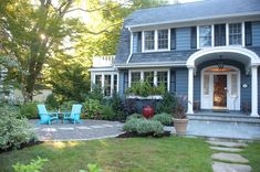 a blue house with two lawn chairs in the front yard