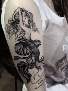 a woman with a mermaid tattoo on her arm