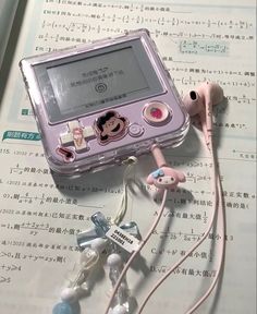 an electronic device with ear buds attached to it sitting on top of some music sheets