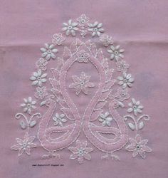 an embroidered design on pink fabric with white flowers