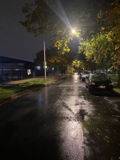 cars are parked on the side of the road in the rain at night with street lights shining