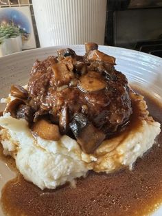 a white plate topped with mashed potatoes covered in gravy