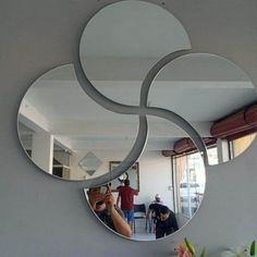 a person taking a photo in front of a mirror with three circular mirrors hanging on the wall