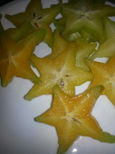 some yellow and green star shaped fruits on a white plate