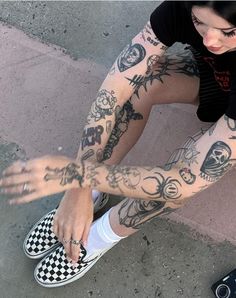 a woman with tattoos on her arm sitting next to a skateboard