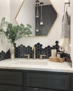 a bathroom with black and white hexagonal tiles on the wall, gold accents