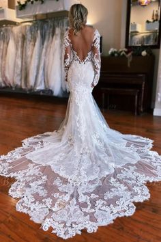 a woman in a white wedding dress standing on a wooden floor with her back to the camera