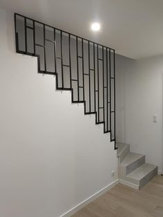 an empty room with white walls and black railings on the wall, next to stairs