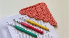 three crochet hooks laying on top of an open book