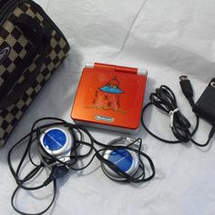 an orange and black bag some headphones and other items on a white sheeted surface