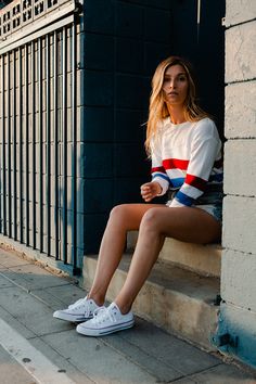 a woman is sitting on the steps in front of a building with her legs crossed