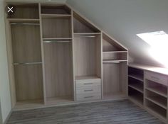 an empty closet with shelves and drawers in the corner, under a slanted roof