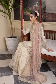 Ivory Embroidered Pakistani Wedding Dress in Kameez Sharara Style is an epitome of elegance and grace that gives you a ravishing appearance on the big day. Embroidery work, gota, sheesha, and zari work make this stunning masterpiece your priority for the wedding. Embroidered Kameez: Beautiful kameez in the graceful ivory shade is emblazoned with graceful goldwork. Lavish embroidery work and gota details give a traditional touch to the kameez. Beaming mirrorwork gives a perfect finishing look to the perfectly stitched white kameez. Sharara: The kameez is paired with the Sharara to create an exquisite Pakistani Wedding Dress. The Sharara has a huge flare and it comes in a beautiful ivory-white color. The borders of this Sharara are adorned with gota, giving a classic touch to the sharara dre Gharara Pakistani Simple, White Gharara Pakistani, White Garara Dress, Pakistani Gharara Designs, White Sharara Suit, White Kameez, White Gharara, Pink Gharara, Gharara Pakistani