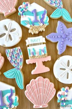 some decorated cookies are sitting on a wooden table with shells and seashells around them