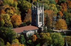 an aerial view of a church surrounded by trees in the fall season with orange and yellow leaves