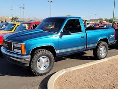 a blue pick up truck parked in a parking lot next to other cars and trucks