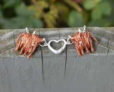 two silver and copper bracelets with elephants on them, one in the shape of a heart