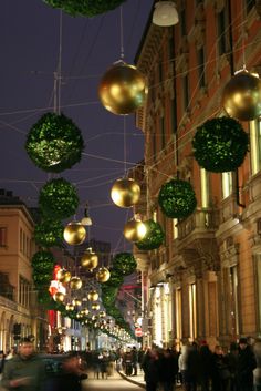 people are walking down the street with christmas decorations hanging from it's ceilings