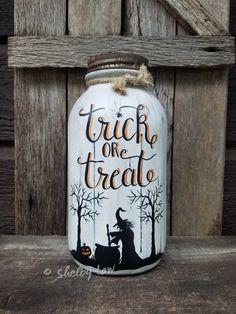 a painted mason jar with the words trick or treat written on it and a witch holding a pumpkin