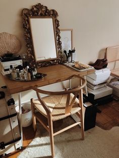 a wooden desk topped with a mirror next to a pile of books and other items