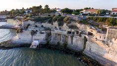 an aerial view of some buildings on the edge of a cliff next to water and houses