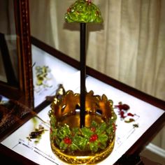 a decorative glass candle holder with holly and berries on it, in front of a mirror