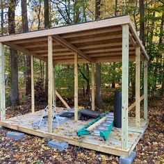 a small wooden structure in the woods surrounded by leaves