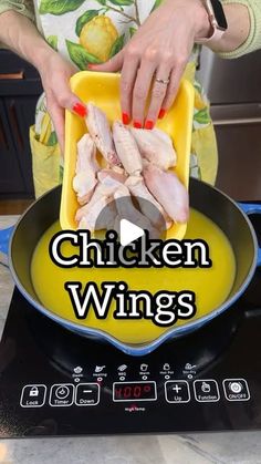 a woman cooking chicken wings in a frying pan on top of an electric stove