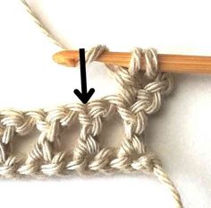 the crochet stitch is being worked on with an arrow pointing up at it