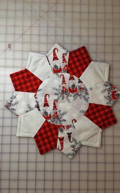 a red and white patchwork quilt on top of a cutting mat