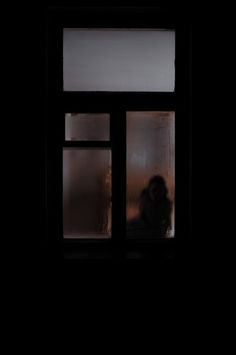 a person standing in front of a window at night