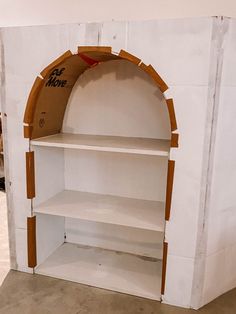 an open white shelf with some writing on the top and shelves below it that are made out of cardboard