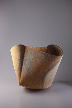 a brown vase sitting on top of a white table next to a gray wall and floor