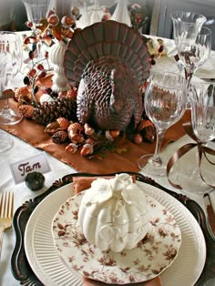 a thanksgiving table setting with turkey and pine cones