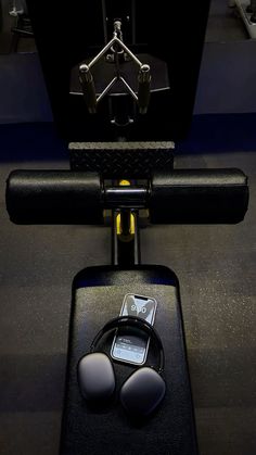 an electronic device sitting on top of a gym floor next to a barbell and weight scale