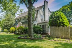 a large house with a flag on the front lawn and trees in the back yard