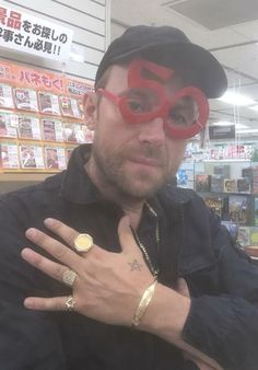 a man wearing red glasses and a black hat with his hand on his chest in front of him