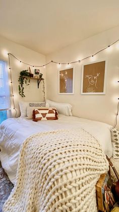 a bedroom with white bedding and string lights