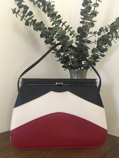 1950s 1960s Miss America By Smartair Top Handle Handbag, Vintage Red White Blue Vinyl Purse, Mid Century Accessory Classic matte red, white and blue vinyl top handle handbag made by Smartair Miss America Handbag in the 1950s 1960s that features: A single vinyl navy blue handle strap. Gold tone metal frame with a thumb lift closure that works well and closes tightly with that lovely "snapping" sound letting you know that everything inside is safe and secure. Opens to a black lining with one inter Vintage Wishlist, Mid Century Accessories, Vinyl Purse, Handbag Vintage, Miss America, Matte Red, Blue Vinyl, Top Handle Handbags, How To Make Handbags