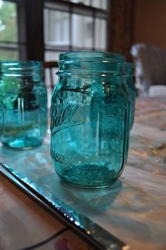 three blue mason jars sitting on top of a table