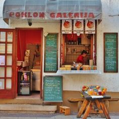 an outside view of a restaurant with menus on the wall and tables in front