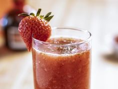 a strawberry sitting on top of a glass filled with liquid