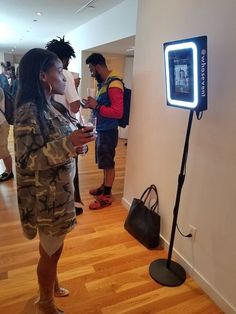 a woman standing in front of a camera holding a cell phone