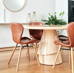 a dining room table with chairs and a potted plant on the end shelf next to it