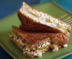 two pieces of sandwich on green plate with fork and blue napkin in the back ground