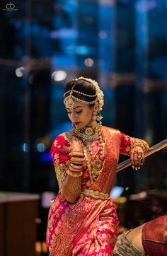 a woman in a red and gold sari is holding her hand on the railing