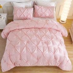 a bed with pink comforter and pillows in a room