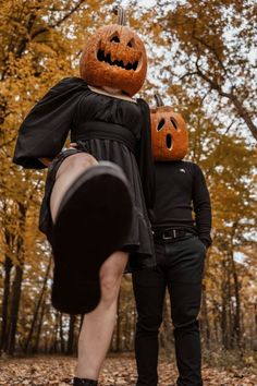 a man and woman dressed up as jack - o'- lanterns in the woods