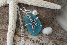 a sea glass necklace with a starfish on it and pearls hanging from the chain