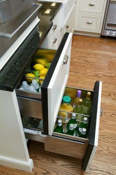 an open drawer in the middle of a kitchen with bottles and lemons on it